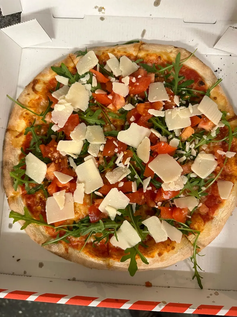 Pizza mit Rucola, Kirschtomaten und Parmesanspänen